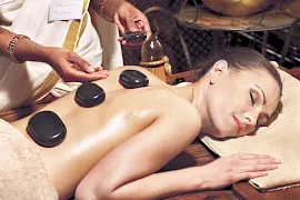 Eine Frau bekommt eine Ayurveda Massage mit heißen Steinen und genießt sie.