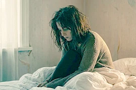 Eine Frau sitzt allein und depressiv zu Hause im Bett. Sie hat eine Trennung erlebt.