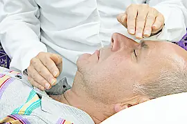 Geistige Heilung durch Handauflegen bei einem liegenden Mann.